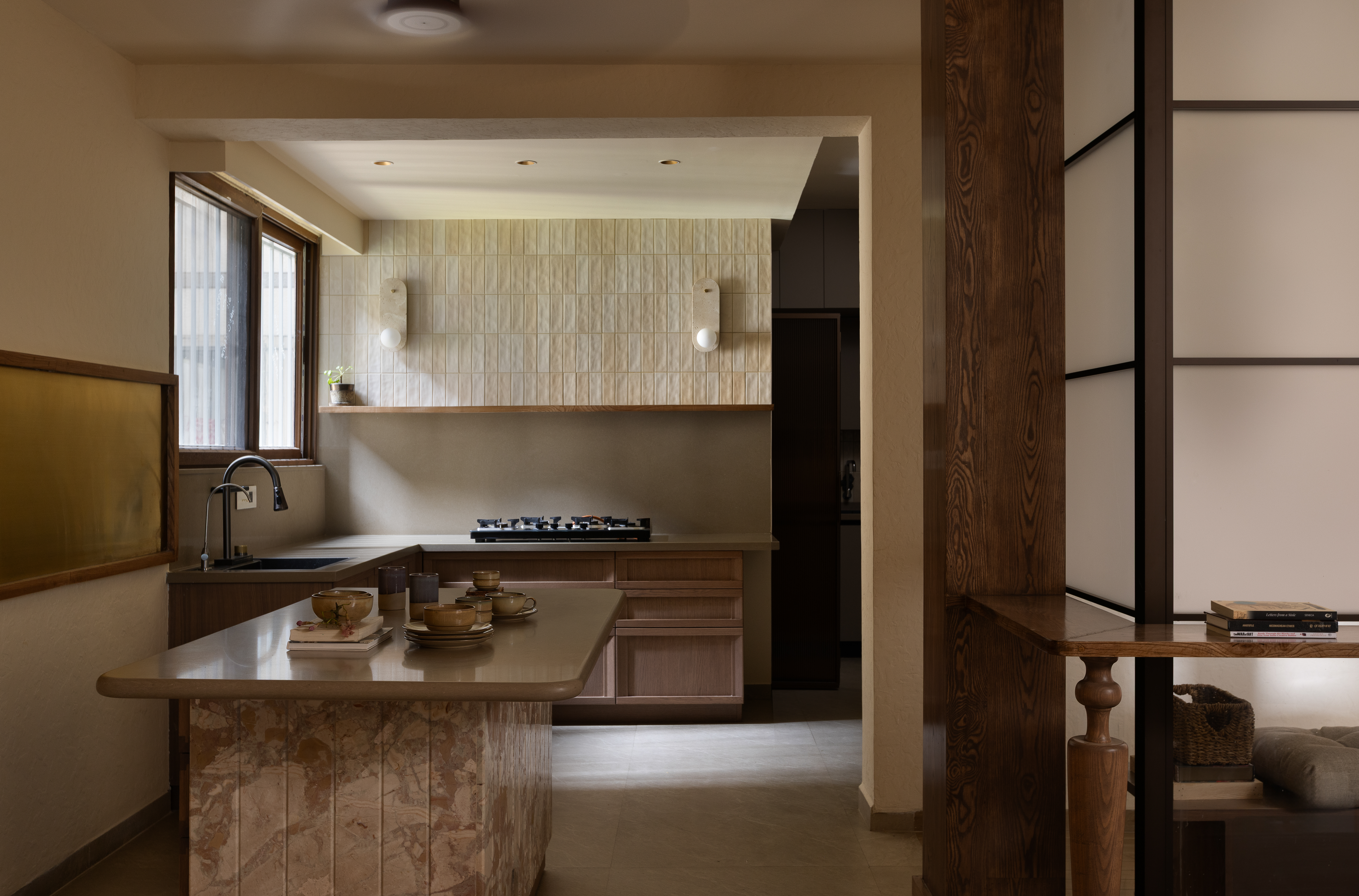 Warm working room with island, bar stools, plants, rhythmic wall panels and shelving