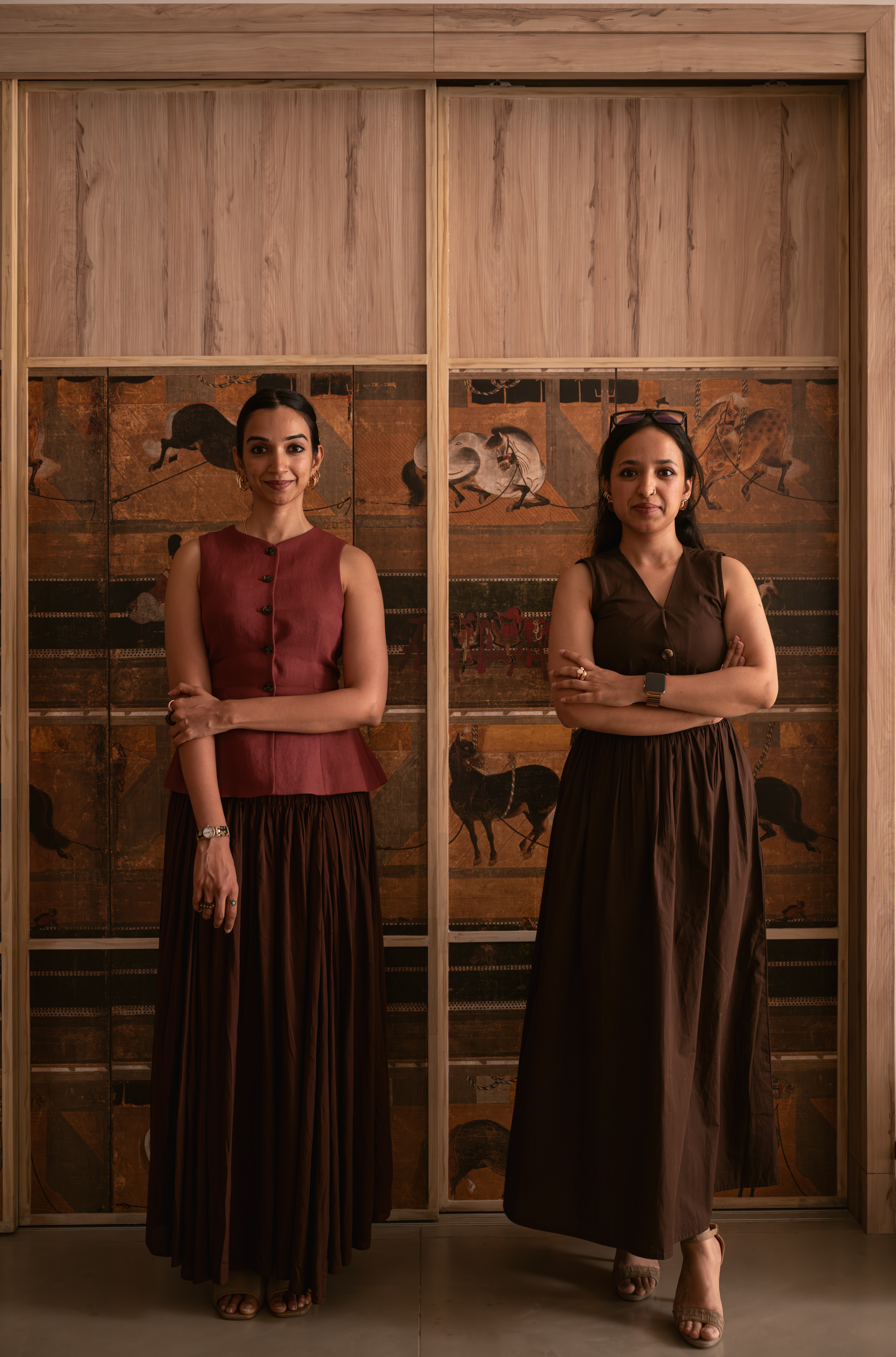 Shvetha and Sanjana, principal architects of The Hippodrome Setting, standing before a hand-painted equestrian panel